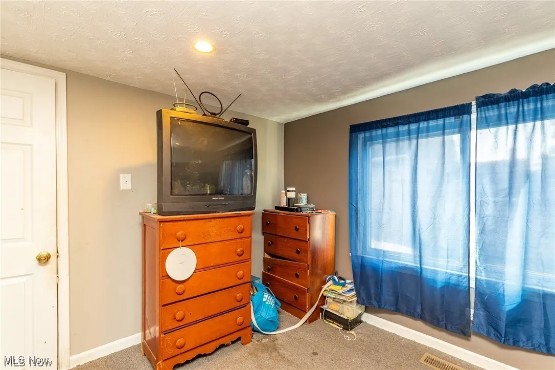 Carpeted bedroom with a textured ceiling and baseboards