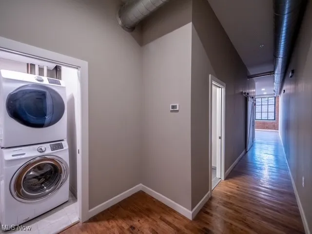 Washroom featuring dark wood-style floors and estacked washer and dryer