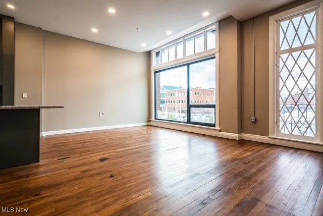 Unfurnished living room with dark wood-type flooring and recessed lighting