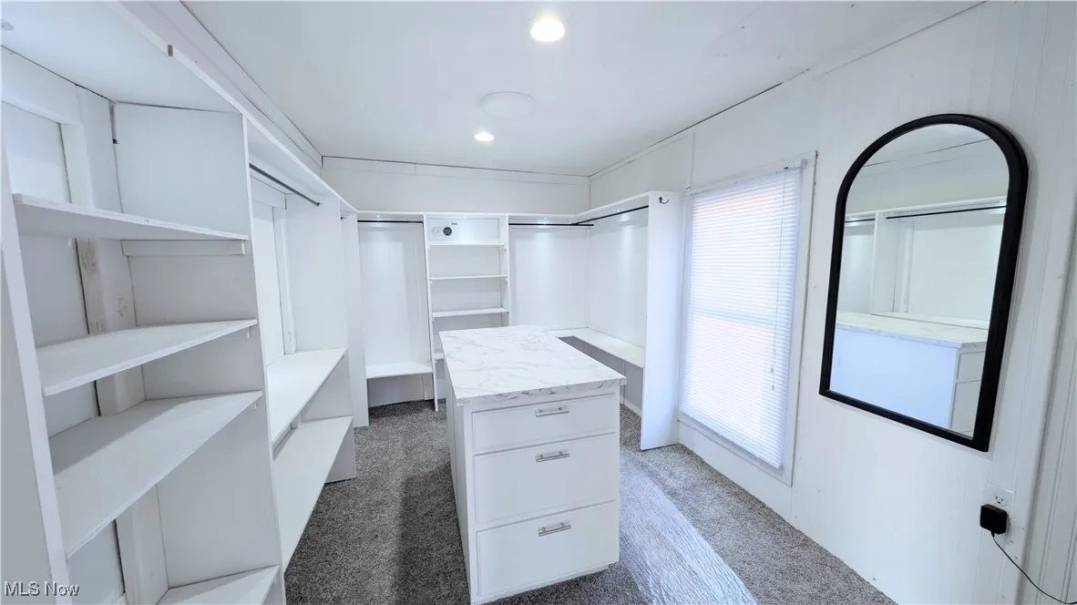 Walk in closet featuring a Closet Island, shelving, and wall safe.