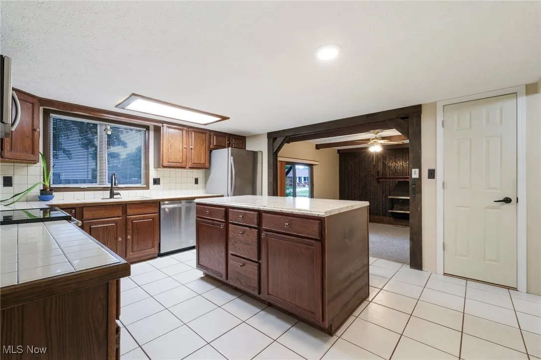 Kitchen with tasteful backsplash, a kitchen island, light tile patterned floors, ceiling fan, and recessed lighting