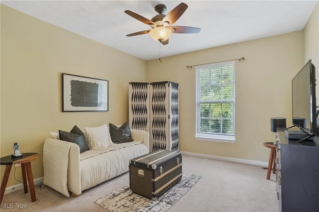 Sitting room featuring carpet flooring, a desk, and a ceiling fan