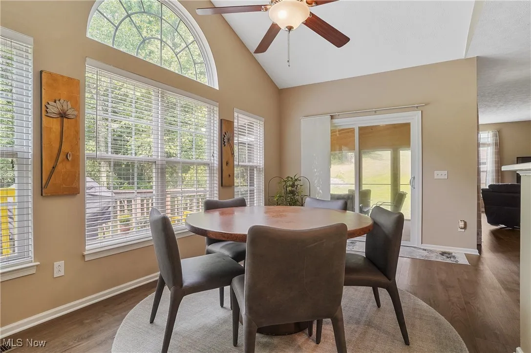Dining area with high vaulted ceiling, plenty of natural light, wood finished floors, and a ceiling fan