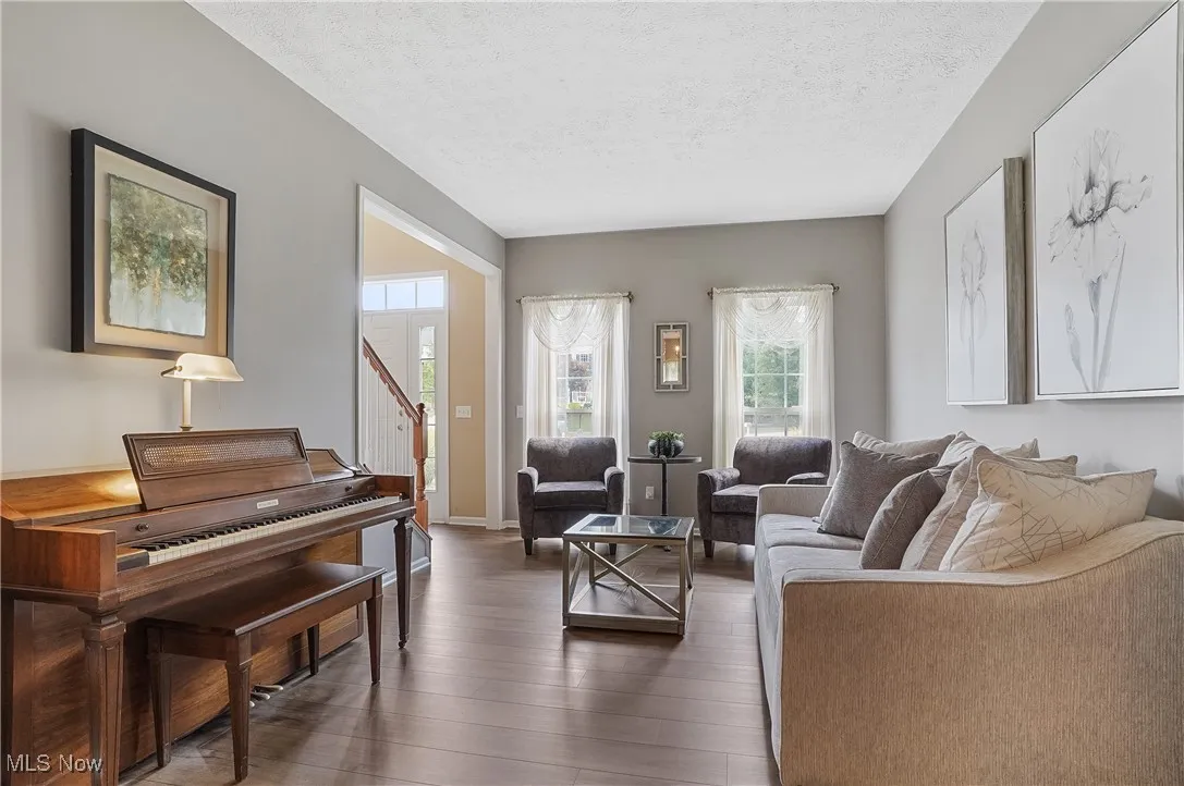 Living room with a textured ceiling, wood finished floors, and stairway