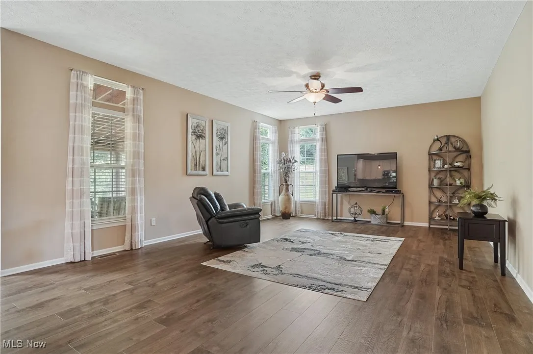 Sitting room with wood finished floors, a textured ceiling, and ceiling fan