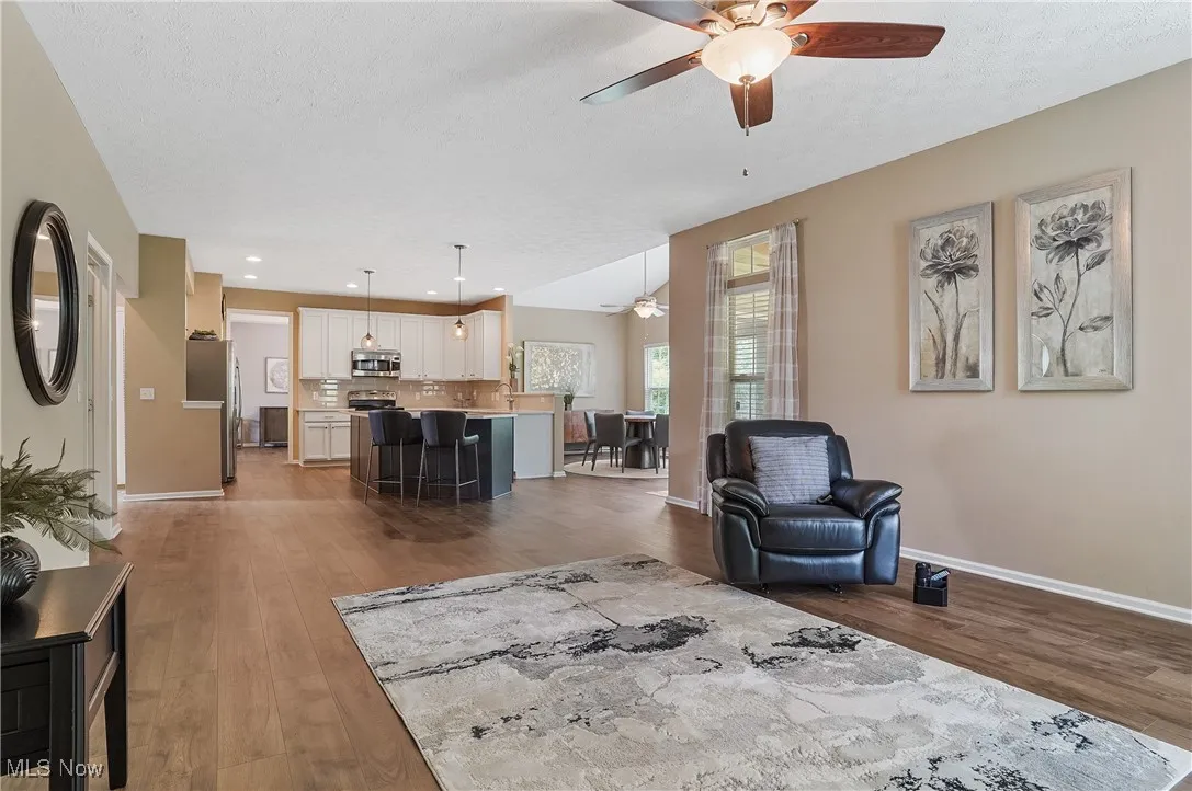 Living room with a ceiling fan, light wood-style flooring, a textured ceiling, and recessed lighting