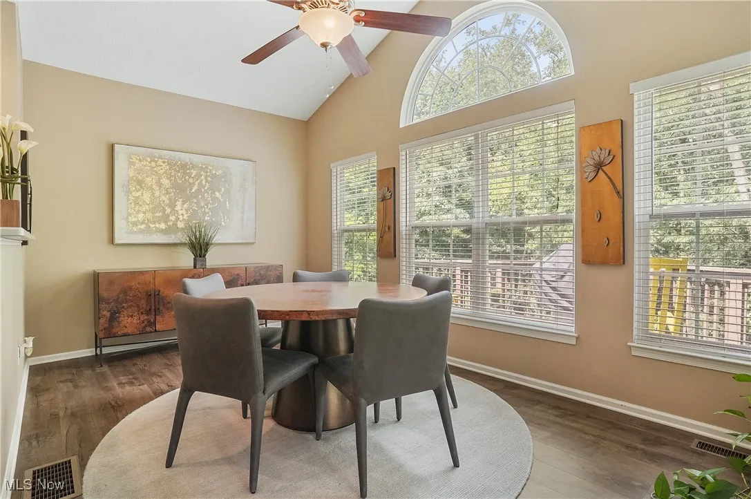Dining space with high vaulted ceiling, dark wood-style floors, and ceiling fan