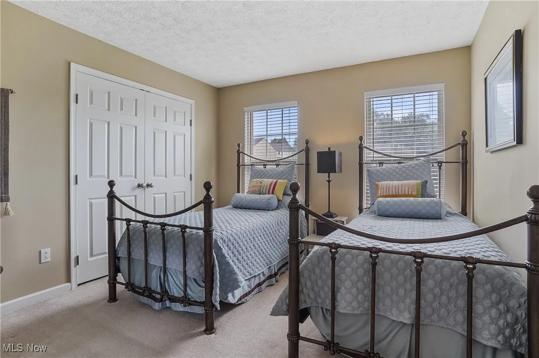 Carpeted bedroom featuring a textured ceiling and a closet