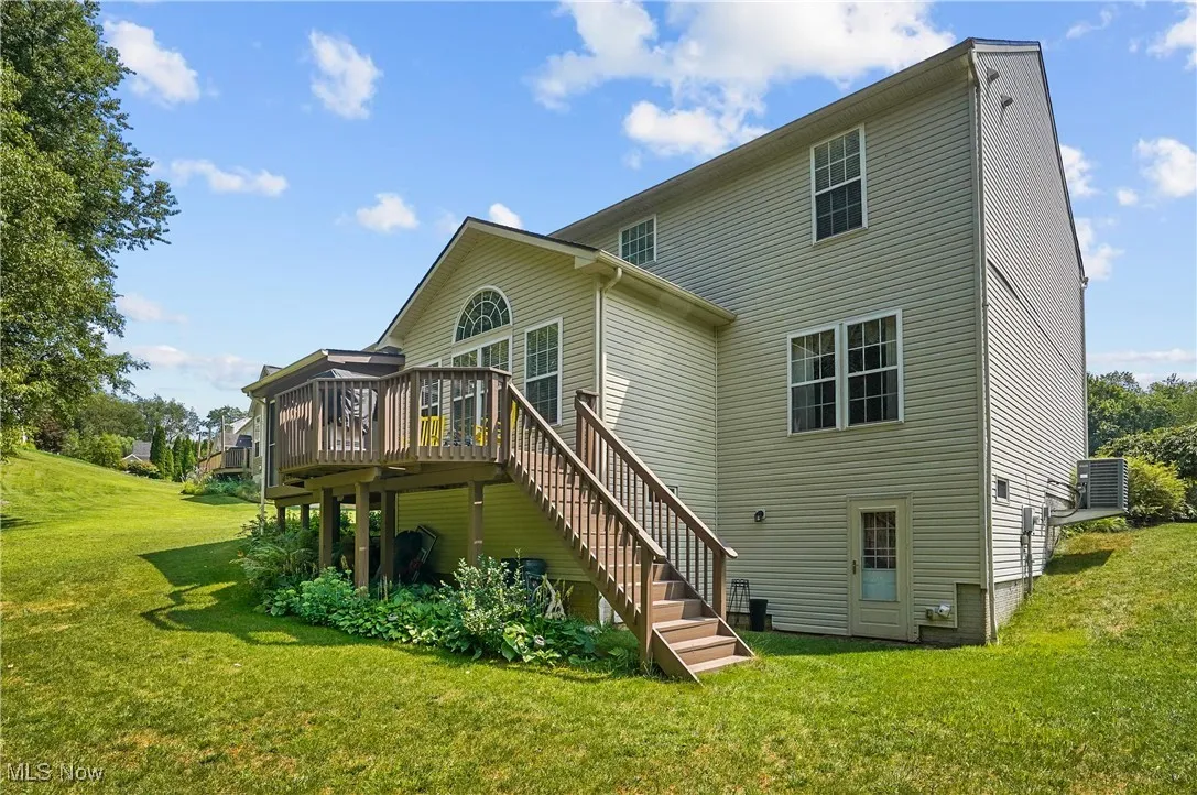 Rear view of house featuring stairway, a deck, and a yard