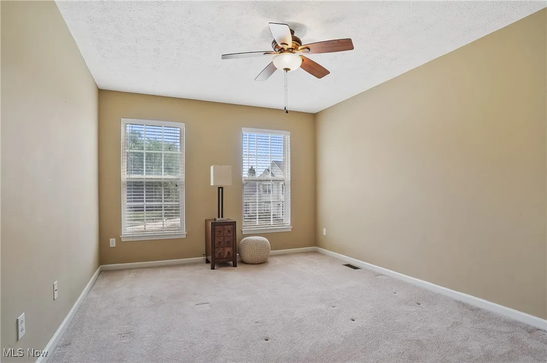 Spare room featuring carpet, a textured ceiling, and a ceiling fan