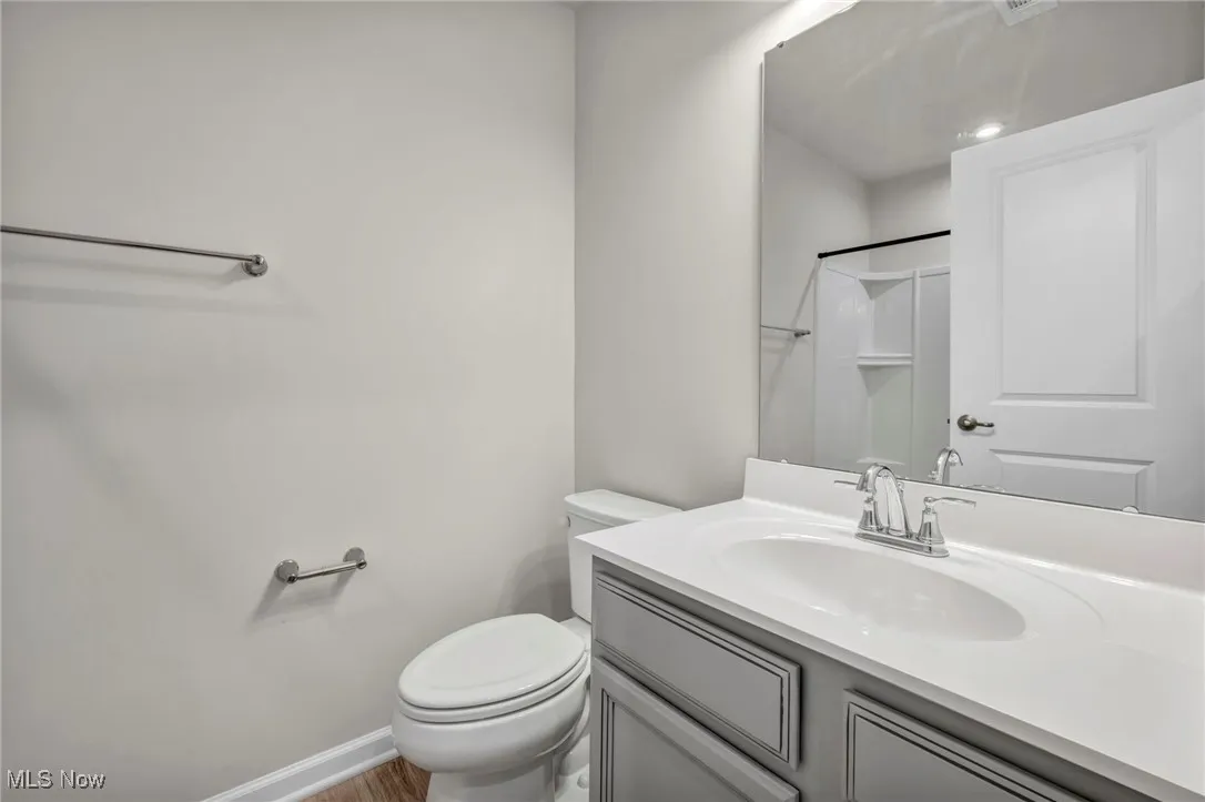 Full bathroom featuring vanity, a shower, and wood finished floors