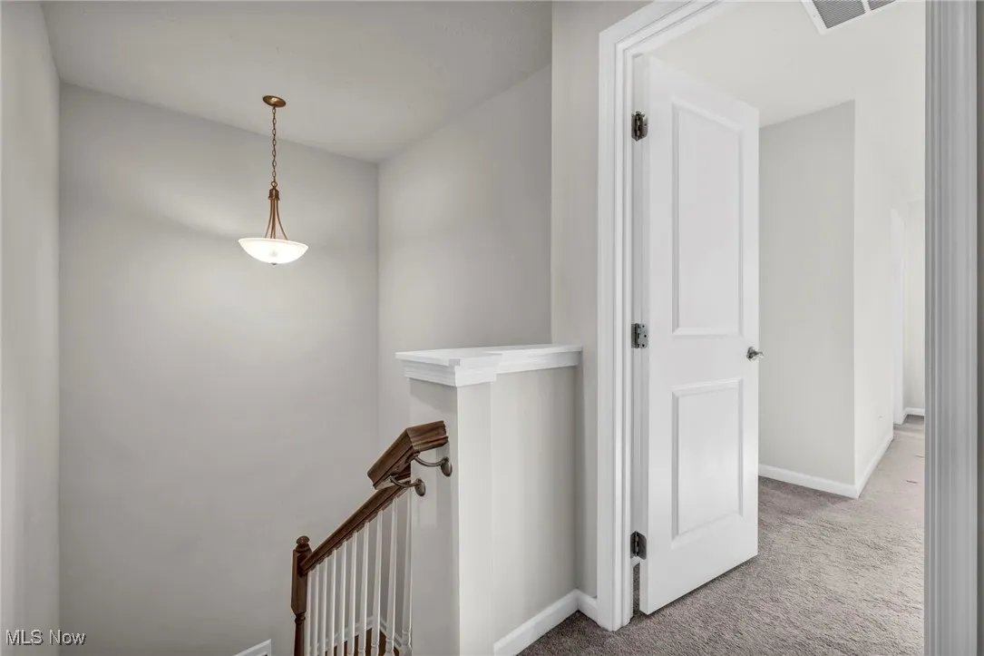 Corridor with an upstairs landing and carpet