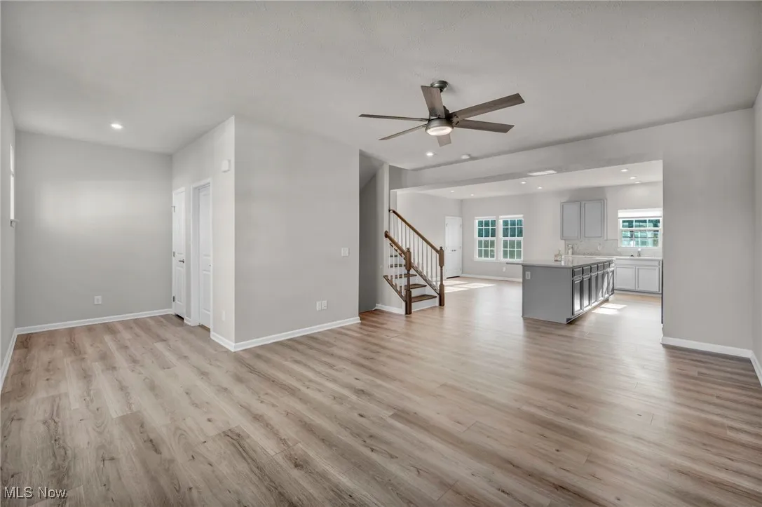 Unfurnished living room with stairway, light wood finished floors, recessed lighting, and a ceiling fan