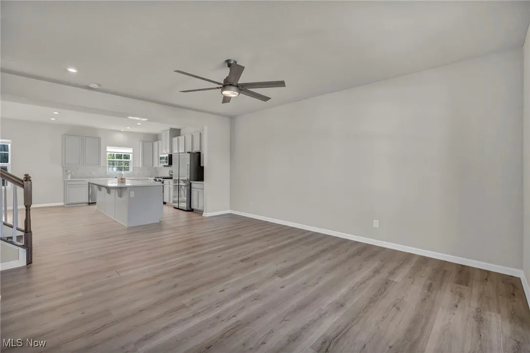 Unfurnished living room featuring light wood-style floors, recessed lighting, a ceiling fan, and stairs