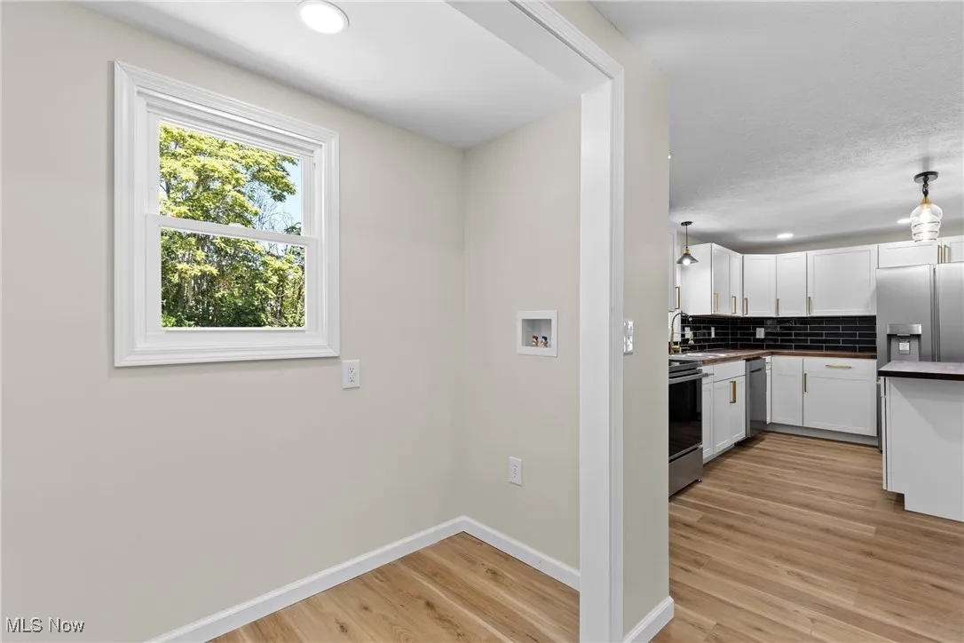 Kitchen featuring decorative backsplash, white cabinetry, light wood-style floors, dark countertops, and recessed lighting