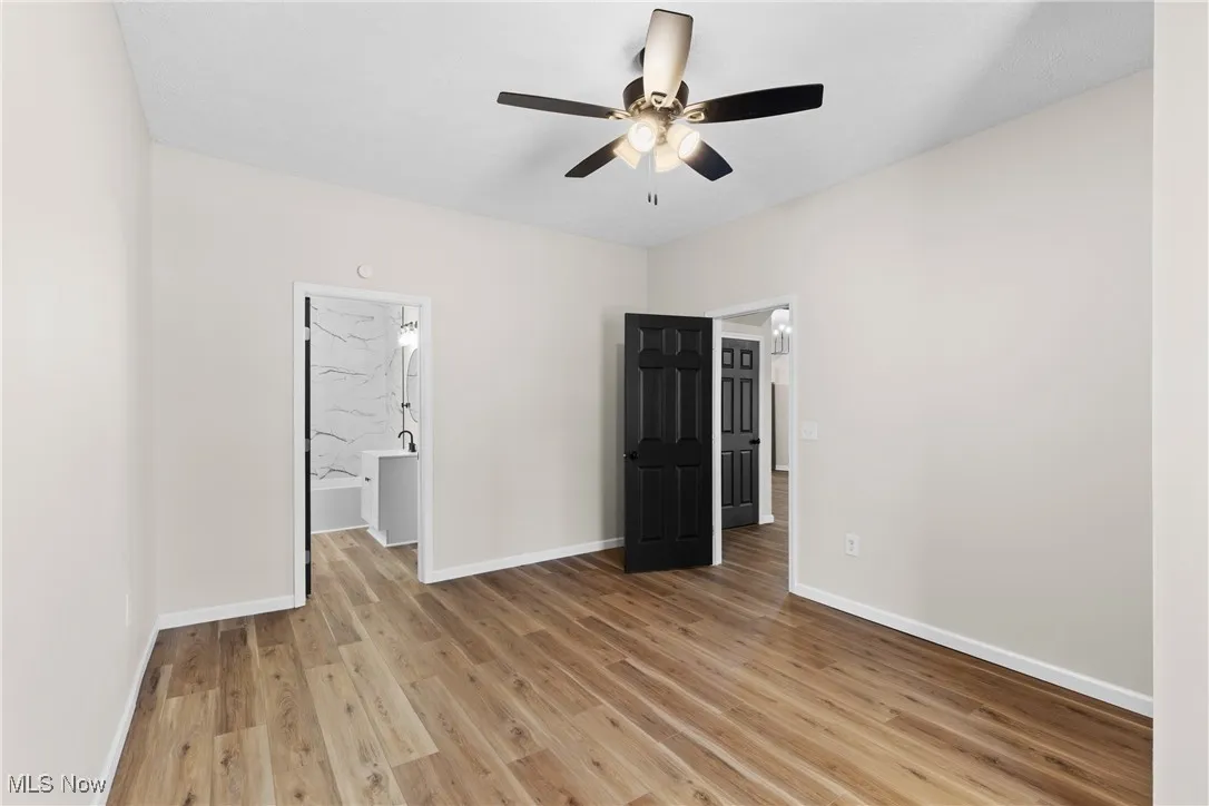 Unfurnished bedroom with light wood-style floors, a ceiling fan, and connected bathroom
