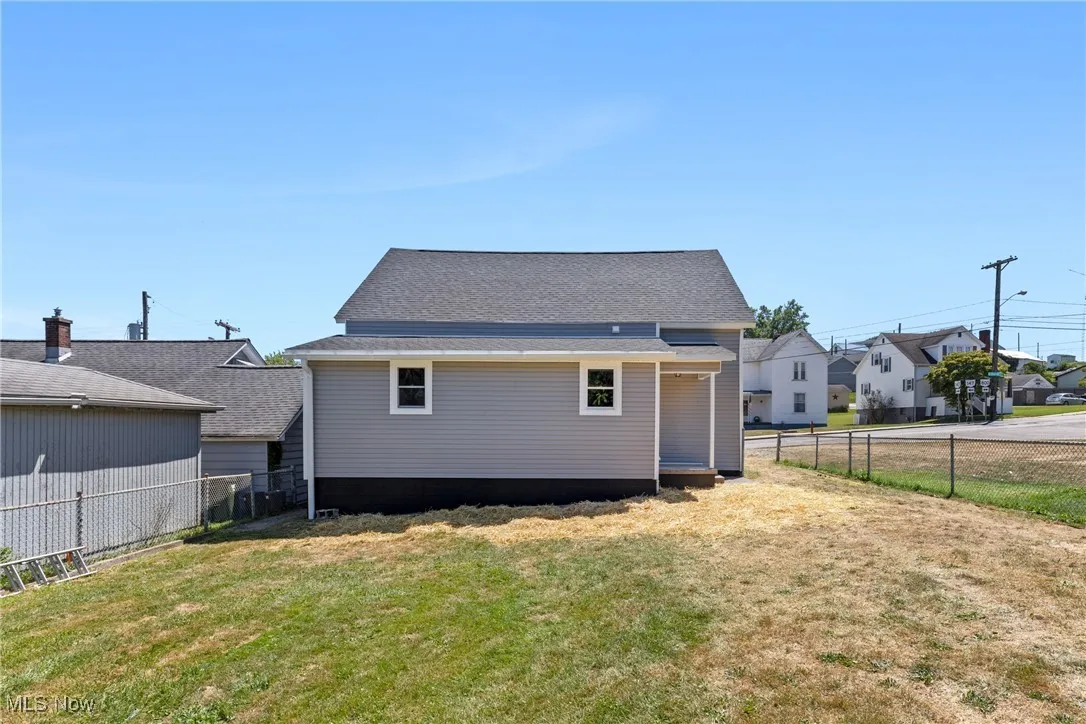 Back of house with a fenced backyard and a shingled roof