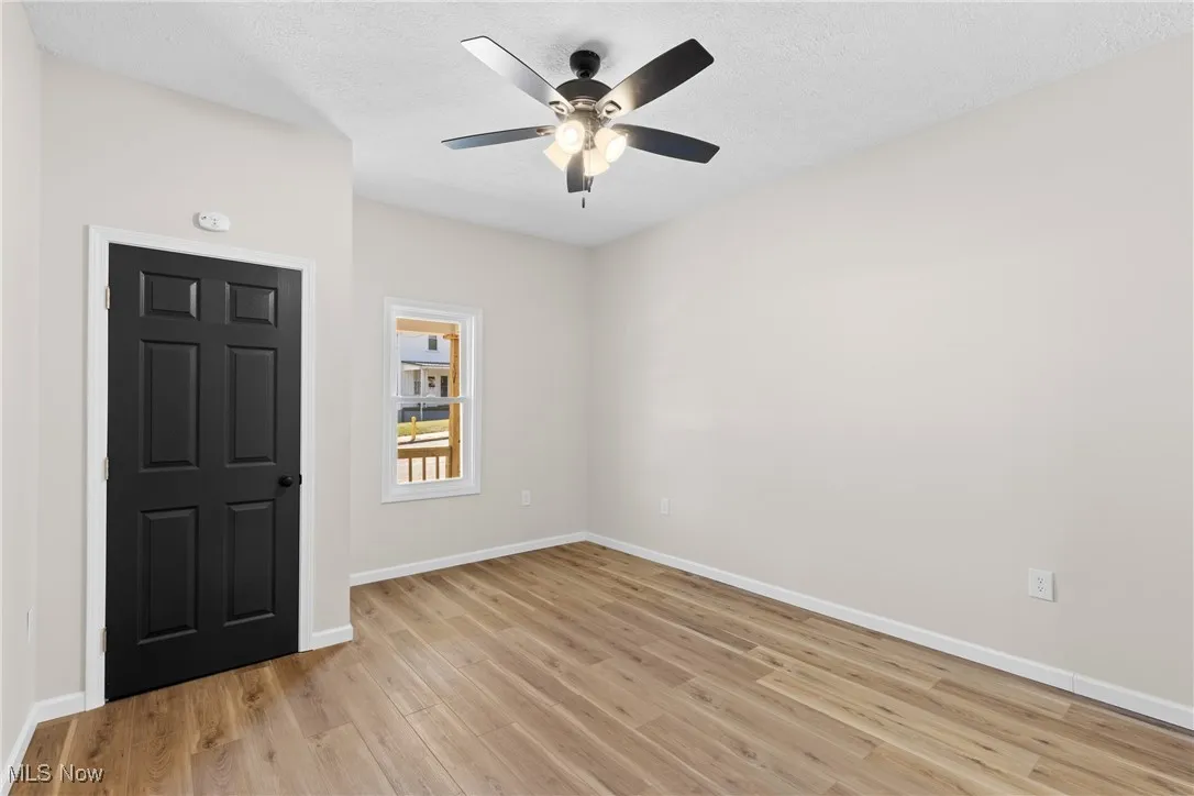 Empty room featuring light wood-style floors, a ceiling fan, and a textured ceiling