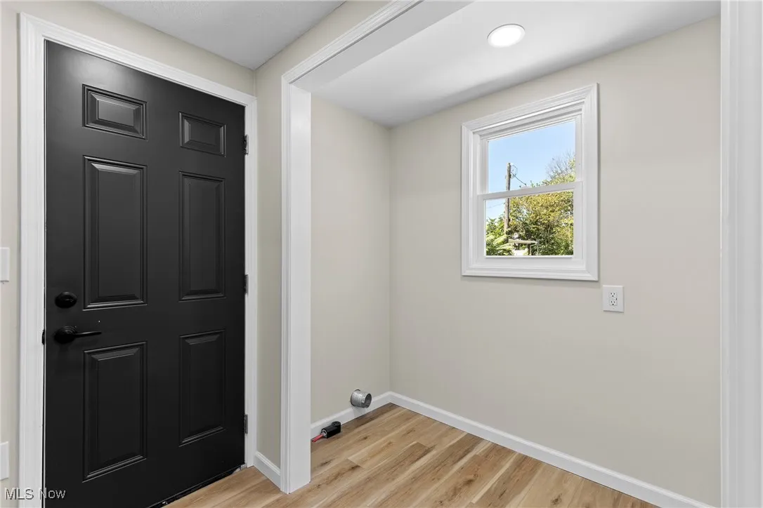Laundry room featuring light wood-style flooring and baseboards