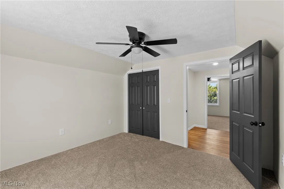Unfurnished bedroom with carpet floors, a closet, a textured ceiling, and ceiling fan