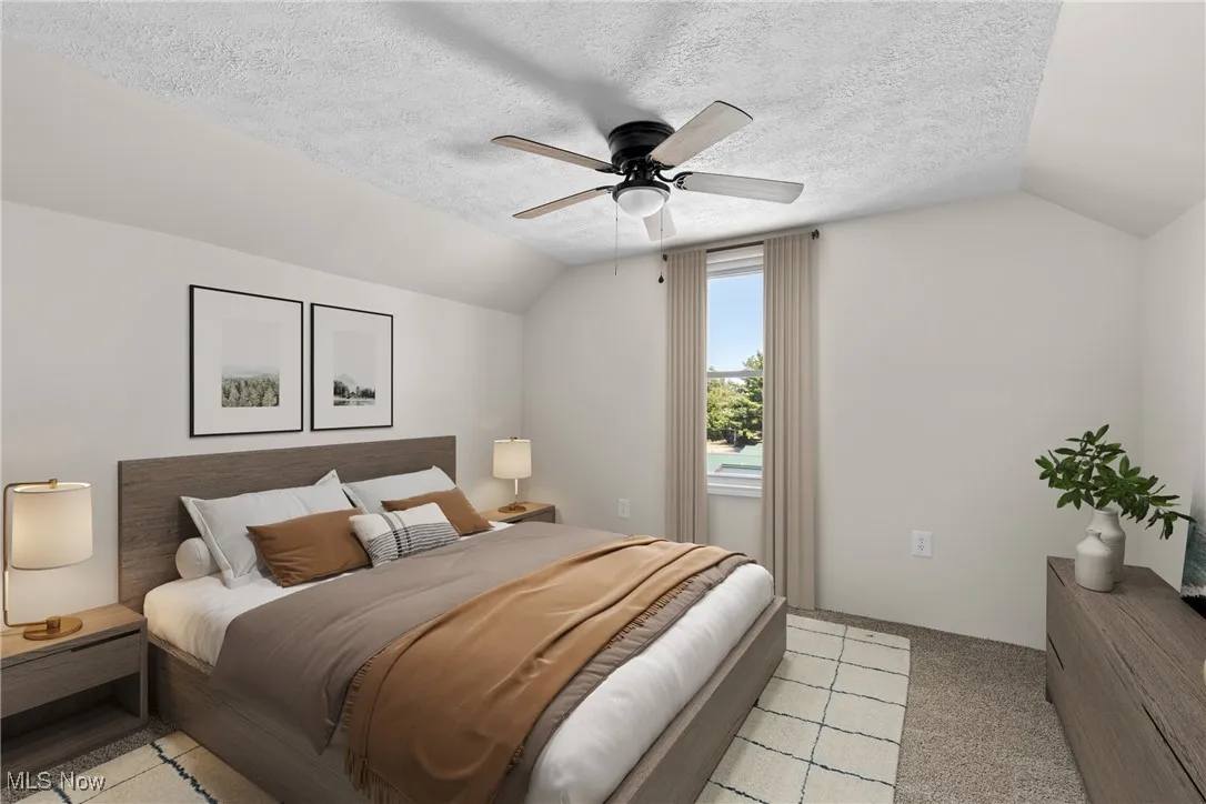 Bedroom featuring vaulted ceiling, light colored carpet, a textured ceiling, and a ceiling fan