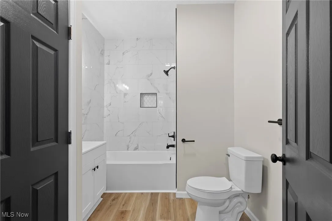 Bathroom featuring vanity, light wood-style flooring, and  shower combination