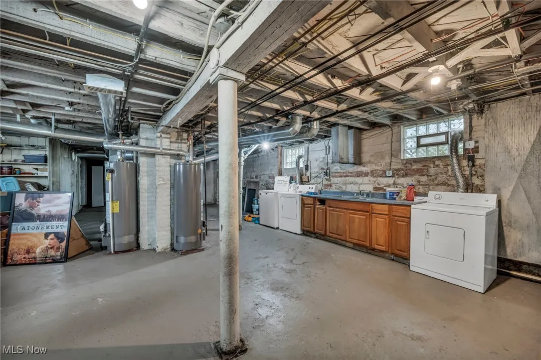 Below grade area featuring water heater and washer and clothes dryer