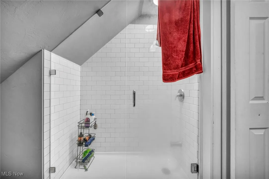 Full bathroom featuring vaulted ceiling and a shower stall