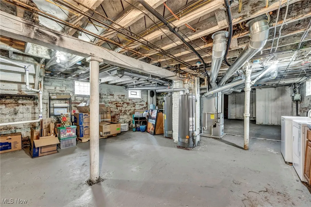Basement featuring gas water heater, heating unit, and separate washer and dryer