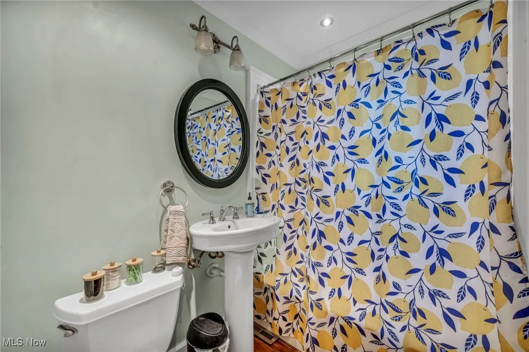 Full bath with toilet and a shower with shower curtain
