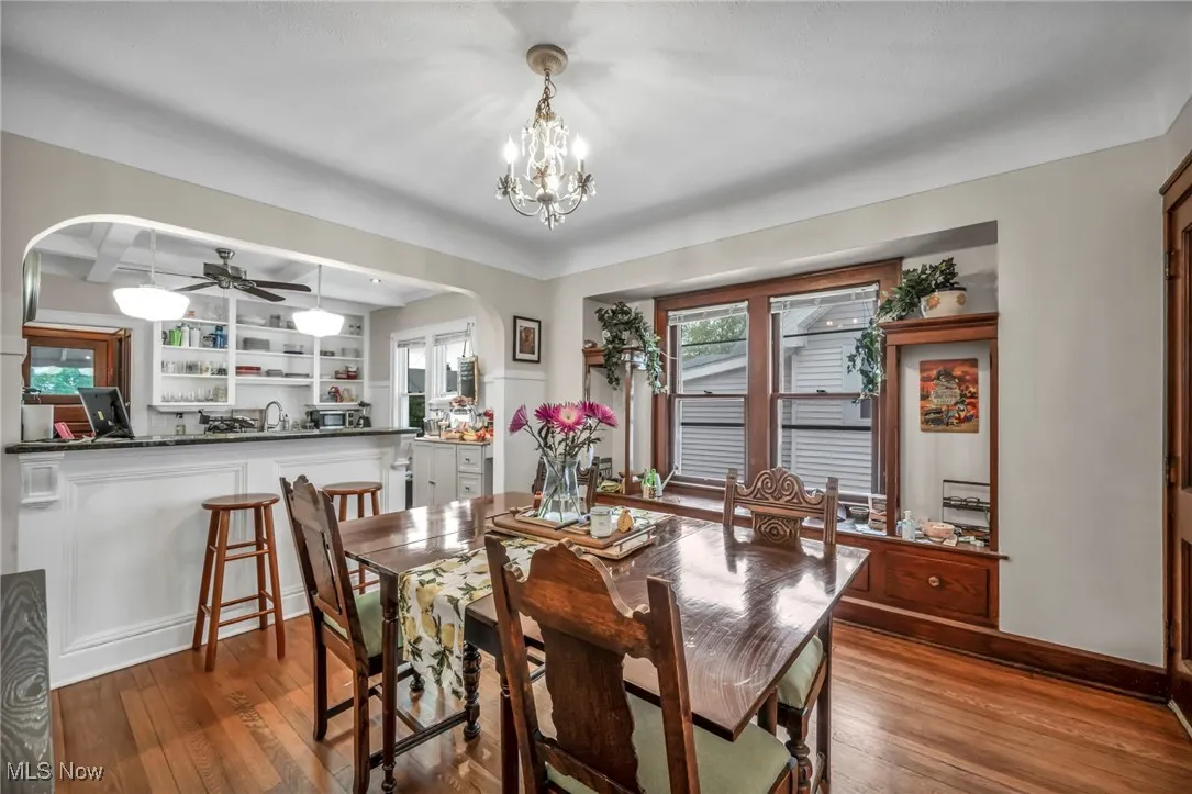 Dining area with arched walkways, hardwood / wood-style floors, a ceiling fan, beam ceiling, and coffered ceiling