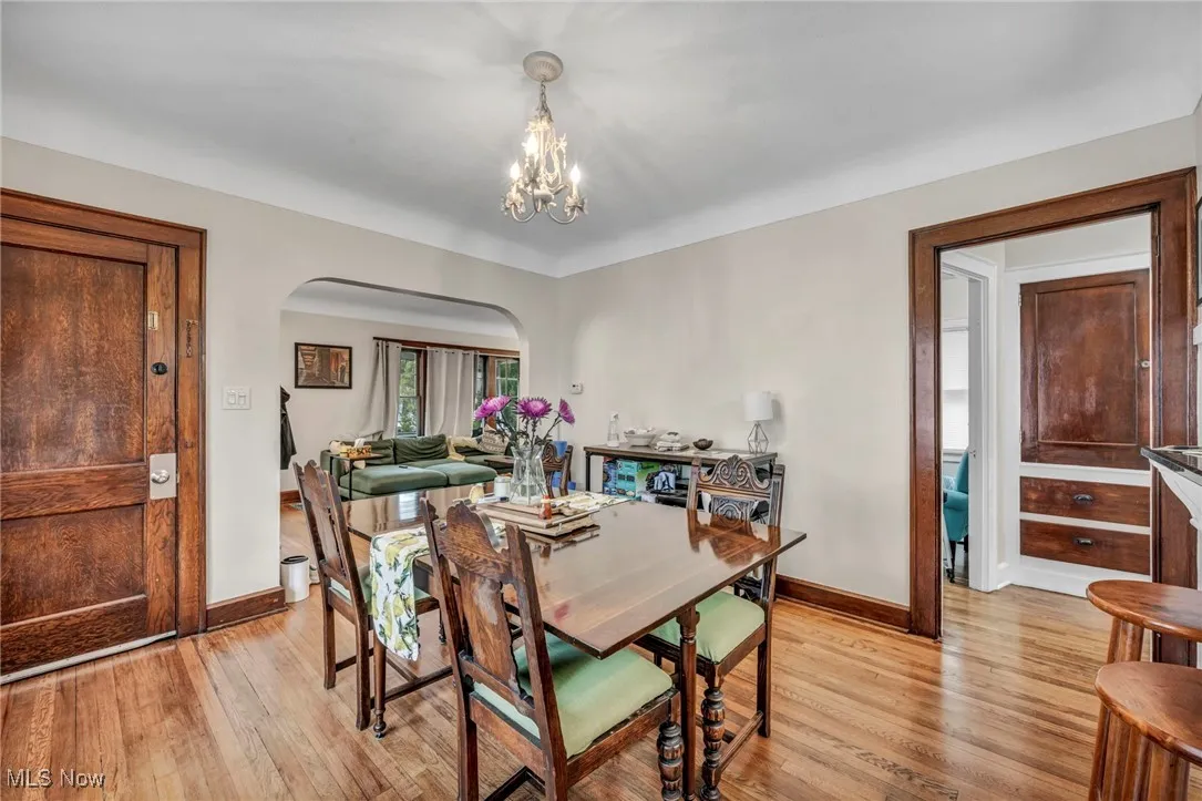 Dining space with light wood-style floors, arched walkways, and a chandelier