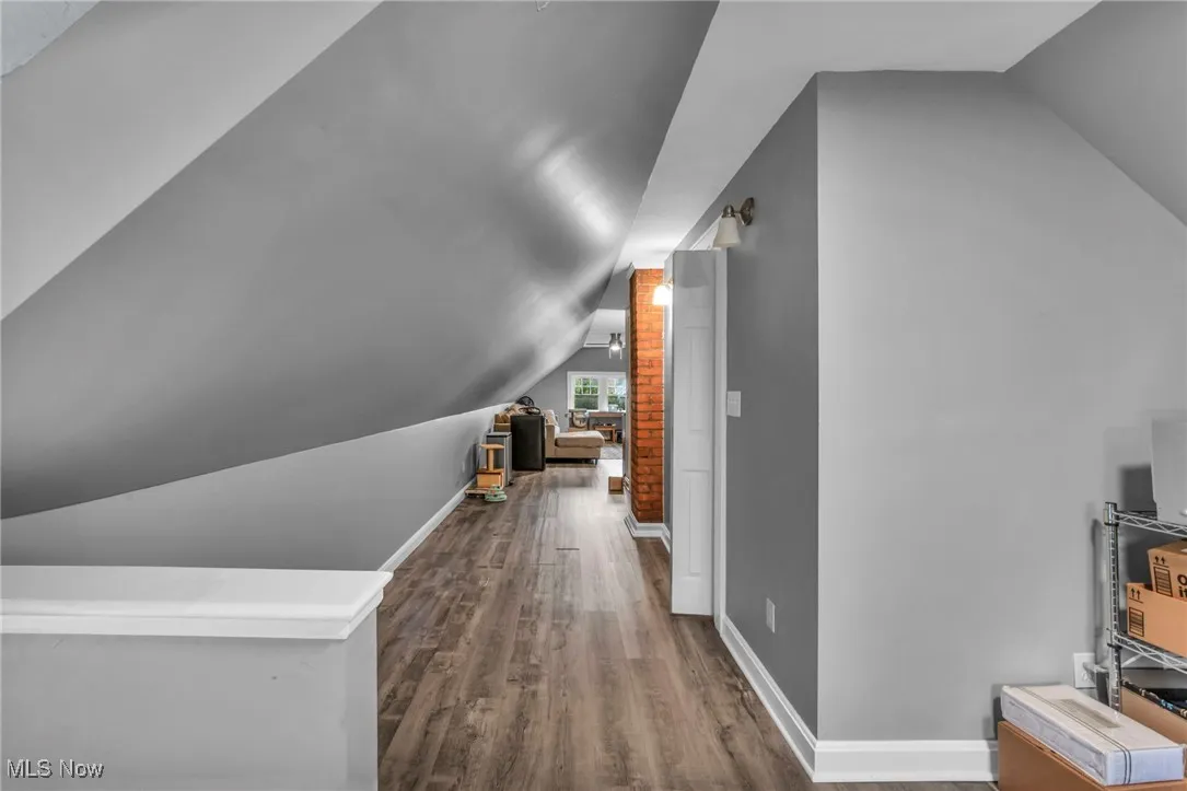 Bonus room with lofted ceiling and dark wood finished floors