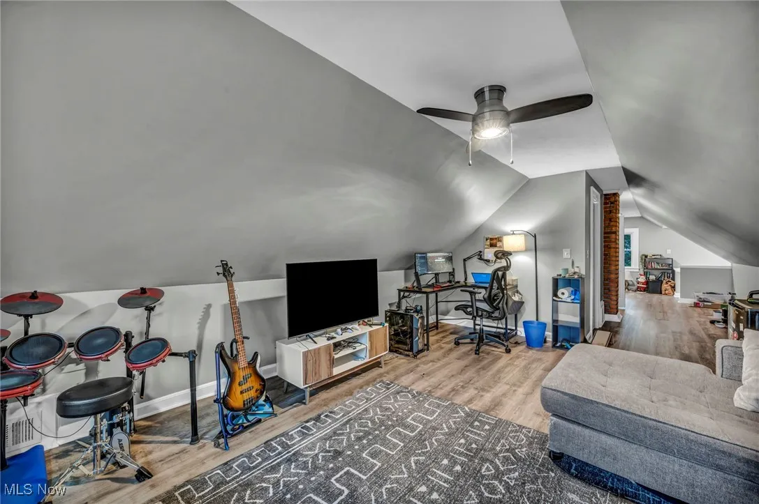 Living room featuring light wood finished floors, vaulted ceiling, and a desk