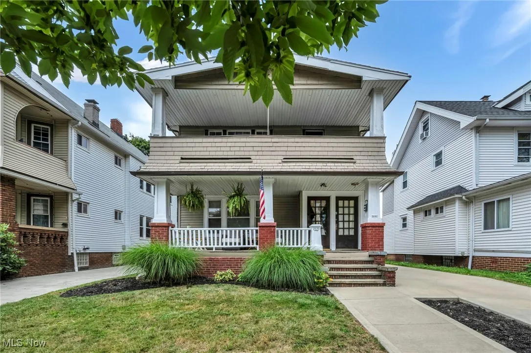 View of front of property featuring a front yard, covered porch, and a balcony