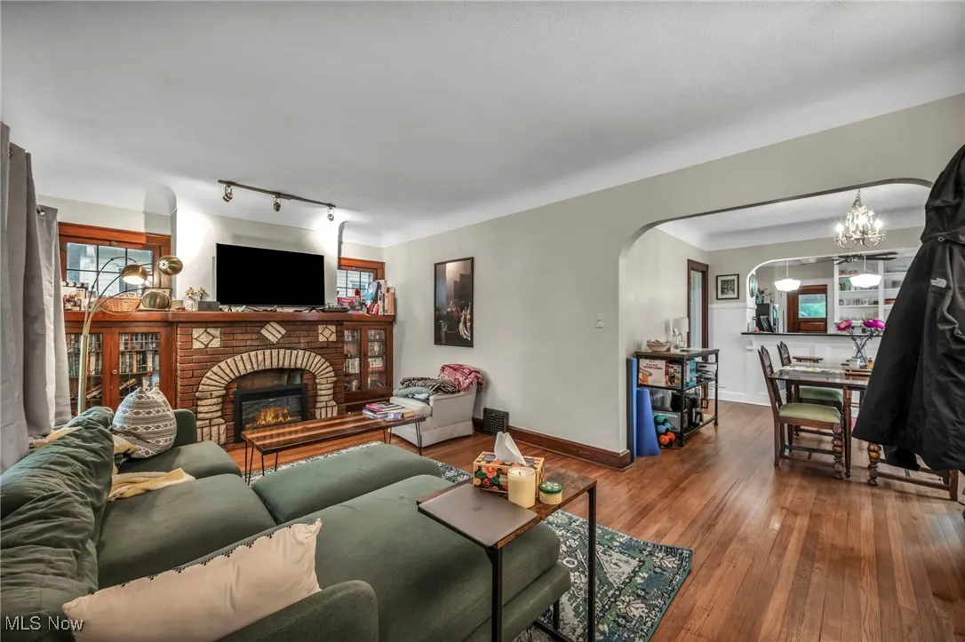 Living area with wood-type flooring, a fireplace, arched walkways, a chandelier, and track lighting
