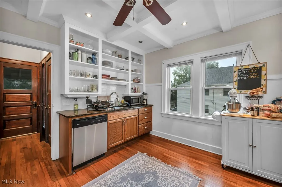Kitchen featuring beamed ceiling, appliances with stainless steel finishes, dark wood-type flooring, open shelves, and dark stone counters