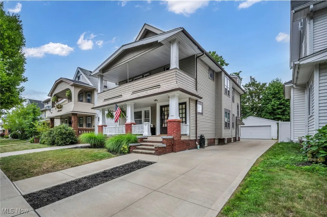 View of front of home featuring a porch, a garage, an outdoor structure, a front yard, and a balcony