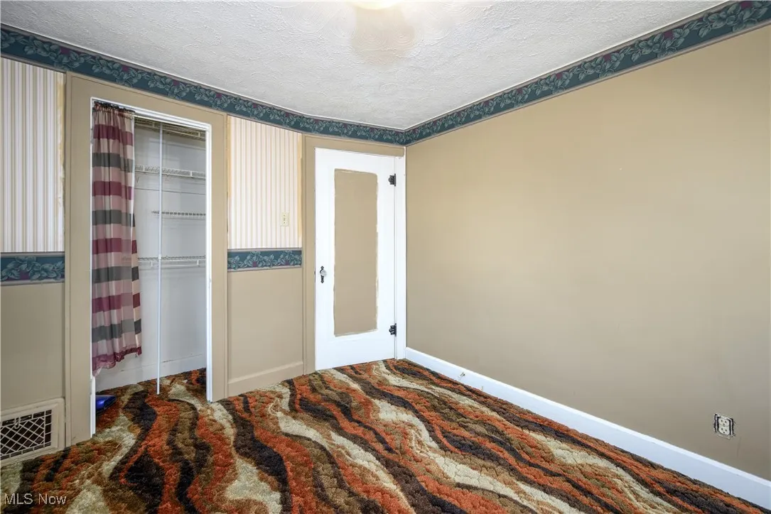 Bedroom with a textured ceiling and a closet
