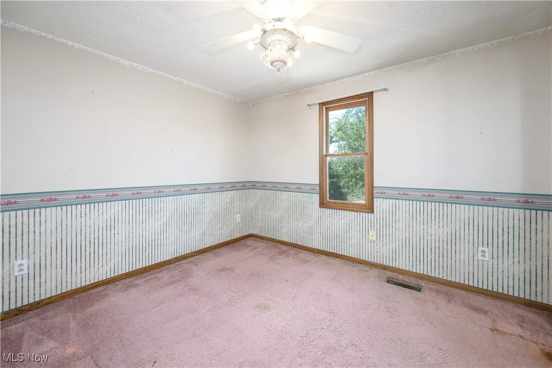 Bedroom featuring a textured ceiling, carpet floors, wallpapered walls, and ceiling fan