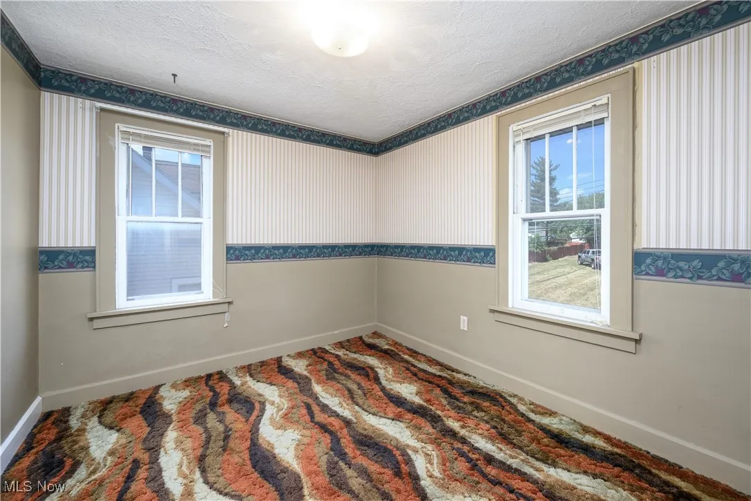 Bedroom with wallpapered walls and a textured ceiling