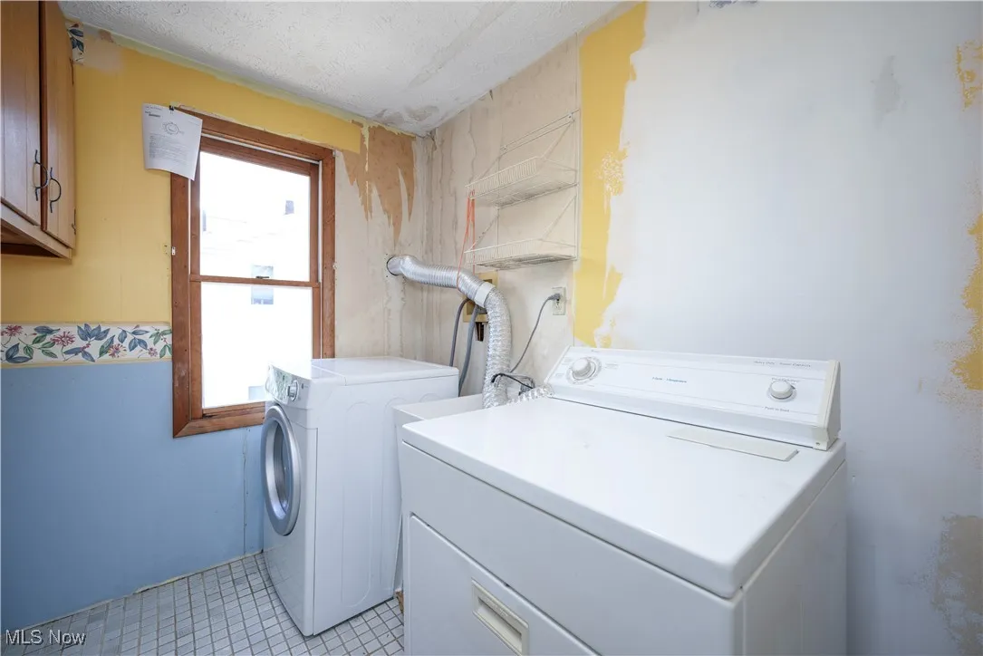 Second floor Laundry area featuring separate washer and dryer, tile flooring, and cabinet space
