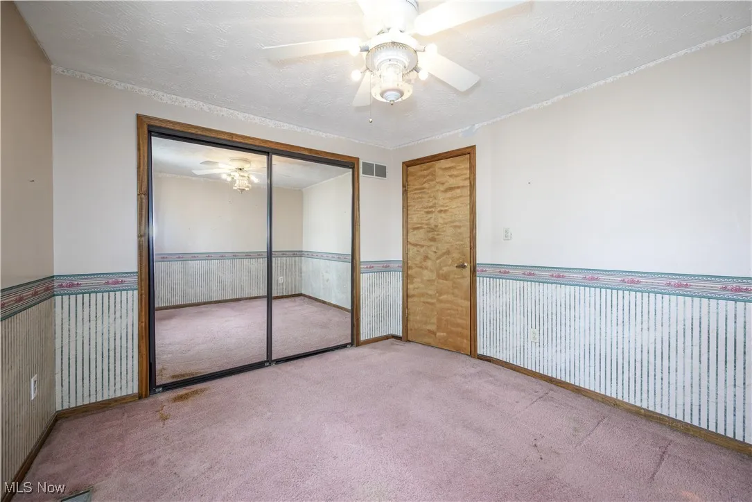 Bedroom featuring a textured ceiling, carpet floors, wallpapered walls, and ceiling fan