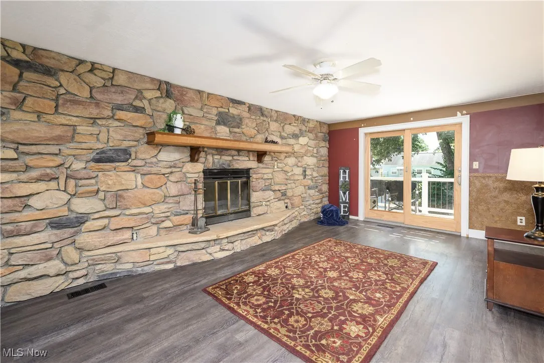 Family room withwaterproof luxury vinyl floors, a stone fireplace, and ceiling fan