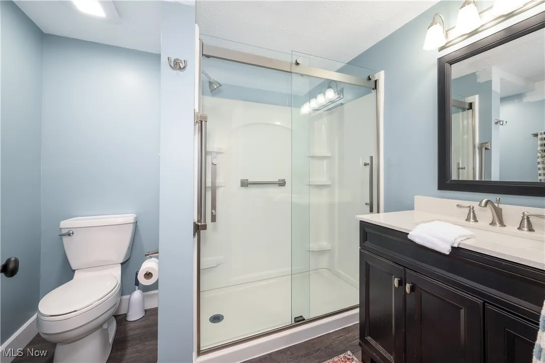First floor full bathroom updated in 2023 featuring vanity, a step-in stall shower with glass doors, waterproof luxury vinyl floor