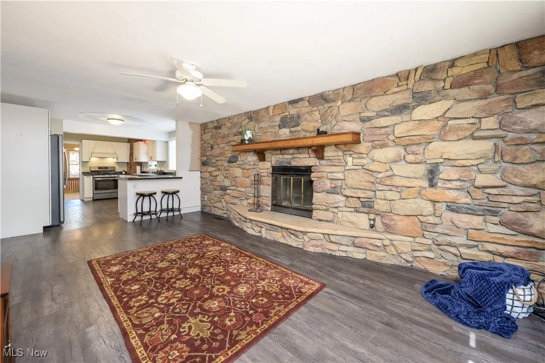 Family room featuring a fireplace, waterproof luxury vinyl floors, and ceiling fan