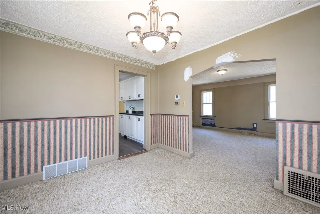 Dining room featuring a textured ceiling, carpet flooring, a chandelier