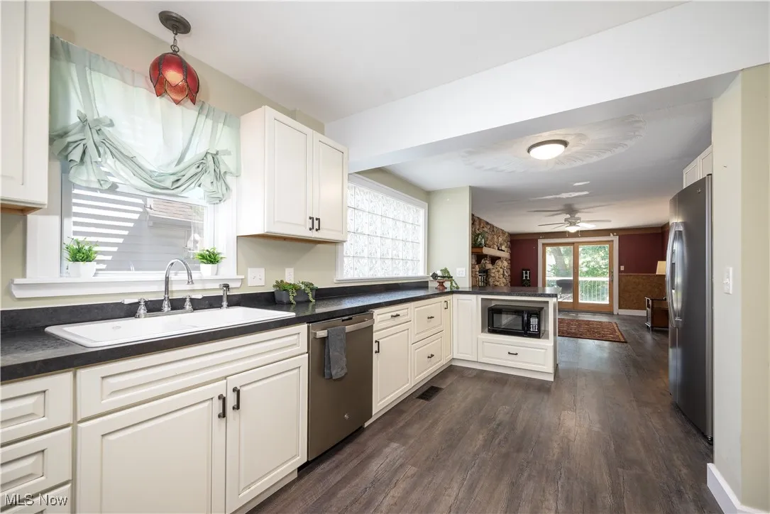 Kitchen featuring a peninsula, dark countertops, waterproof luxury vinyl floors, appliances with stainless steel finishes, and white cabinets