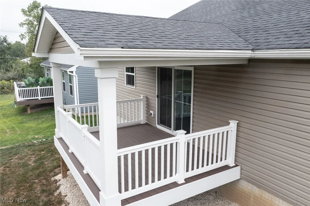 Covered composite deck overlooking trees and a pond.