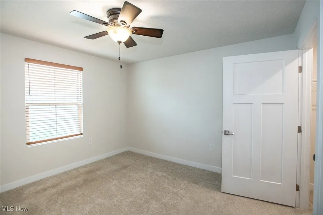 Bedroom 2 with walk in closet, ceiling fan and custom blinds